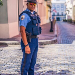 Uniformed police officer stands on a cobblestone street, ensuring public safety.